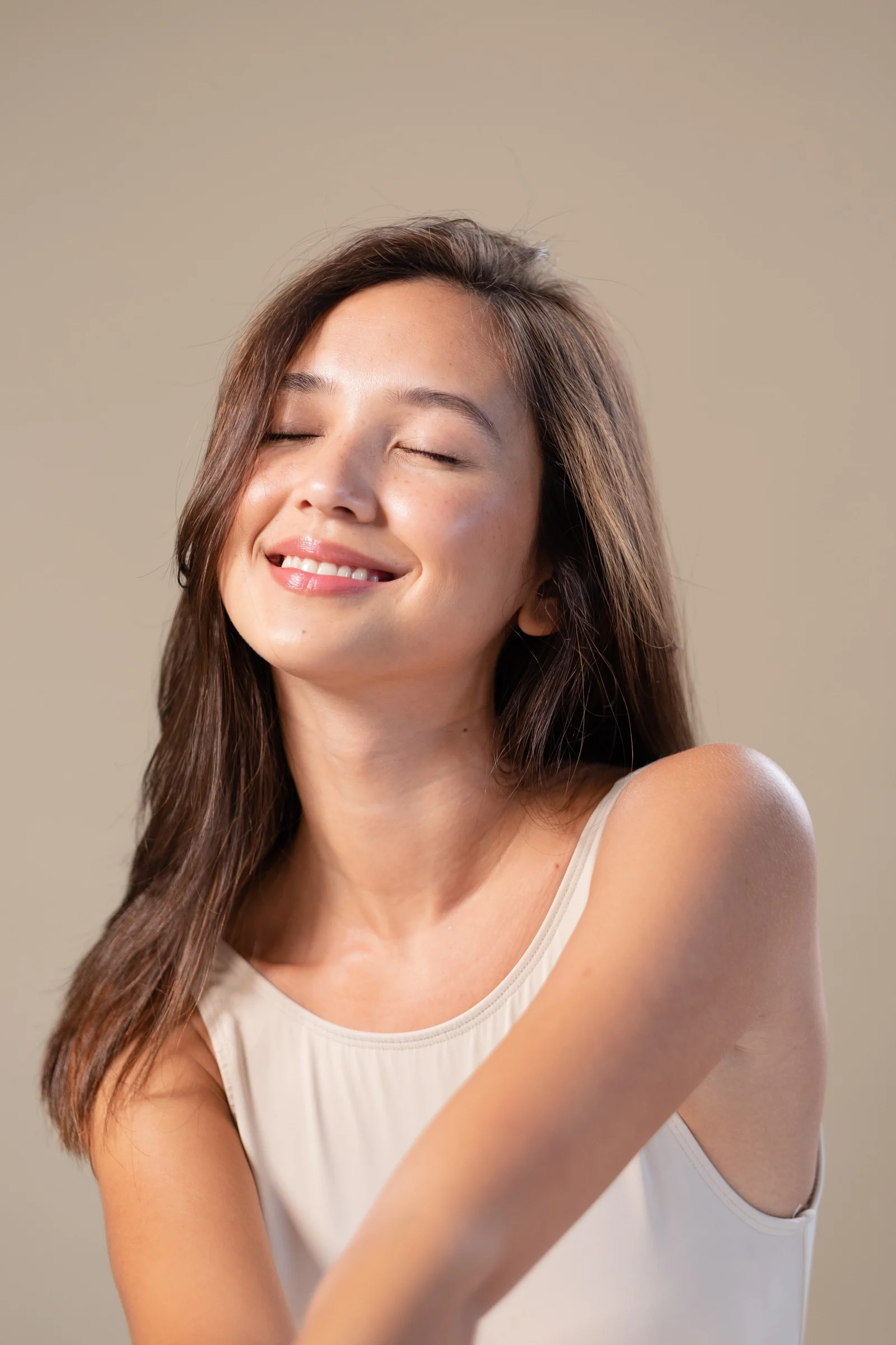 Close-up of hands holding a small glass bottle with a liquid skincare product, against a soft, blurred background